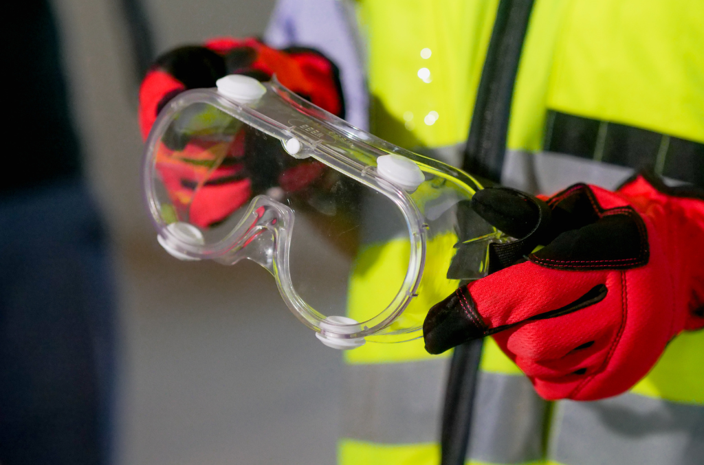 a worker holding safety glasses