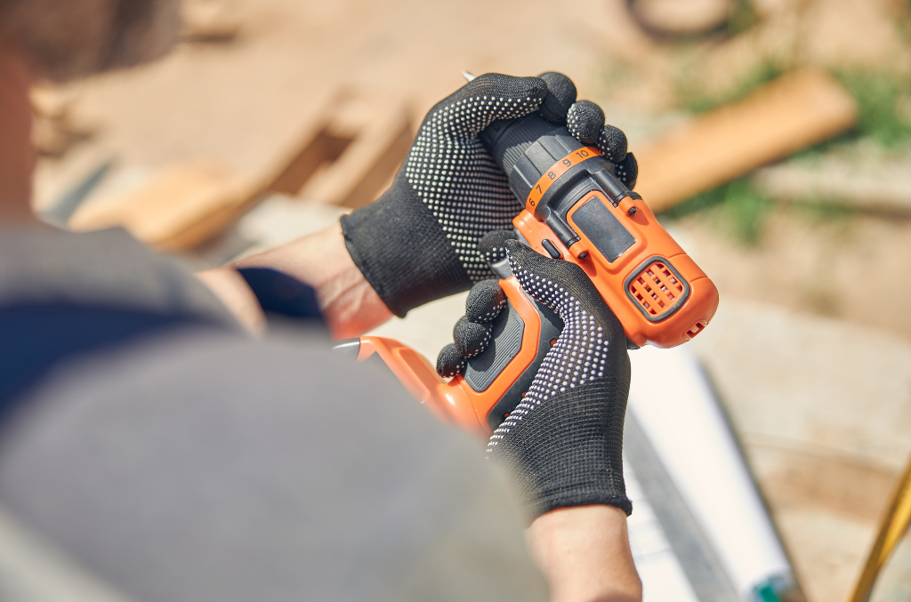 a guy holding a power drill with cut resistant gloves