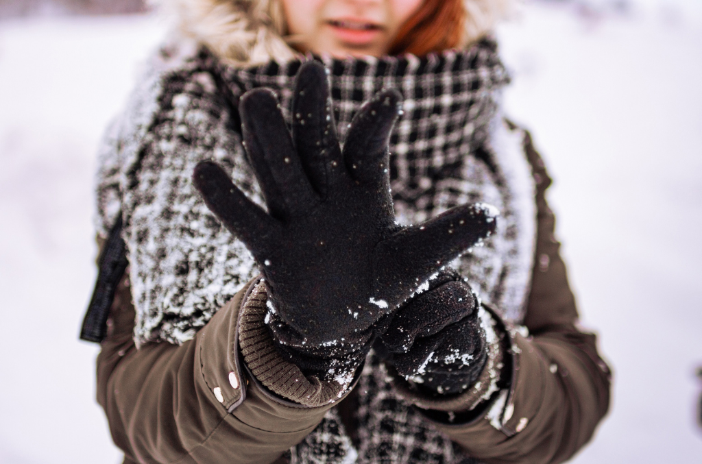 a woman wearing black cold protection gloves